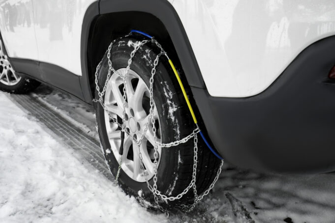 Používateľ inštaluje snehové reťaze na auto počas zimnej jazdy