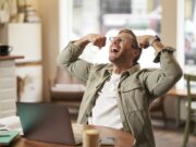 Ako sa zbaviť dlhodobého stresu za 1 mesiac Muž s úsmevom dvíhajúci sa ruky v geste víťazstva po úspešnom zvládnutí stresu.