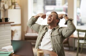 Ako sa zbaviť dlhodobého stresu za 1 mesiac Muž s úsmevom dvíhajúci sa ruky v geste víťazstva po úspešnom zvládnutí stresu.