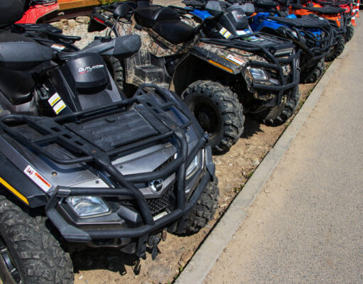 Ktorý typ štvorkolky sa hodí k vášmu životnému štýlu? Rôzne typy štvorkoliek – športová, úžitková a rekreačná, zaparkované na lúke alebo pri lese.