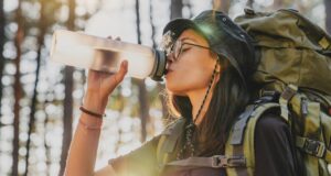 Ako si vybrať správnu fľašu na vodu do hôr? Turistická fľaša na vodu položená na skale s výhľadom na horskú krajinu